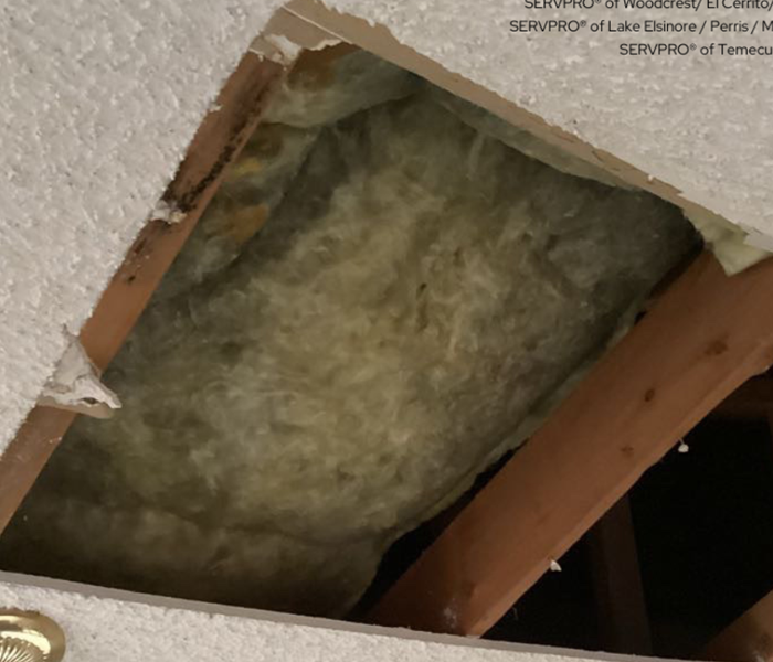 A water-damaged ceiling with a part of it taken out and it has insulation inside