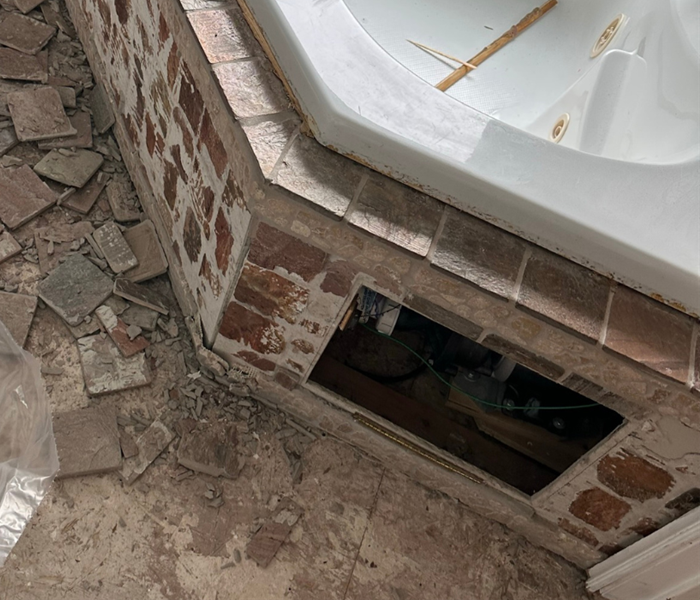a water damaged bathtub with tiles and flooring being taken out